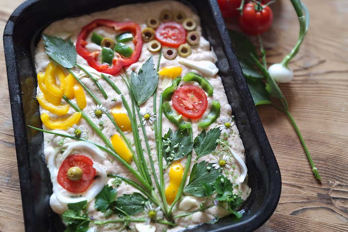 Rozkvitnutá foccacia, ozdobený taliansky chlieb zeleninou a bylinkami